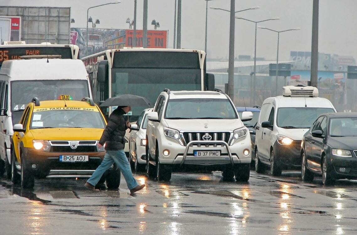 Cars and trucks stopped as a pedestrian crosses the street on a rainy day | Rubber products